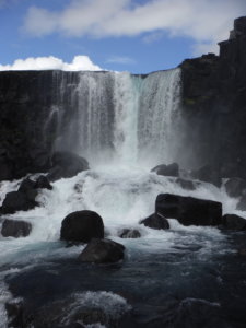 Thingvellir National Park contains the spectacular Oxarfoss waterfall spilling over a cliff onto large boulders below