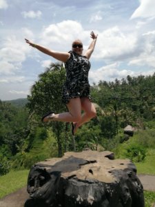 A photo of me jumping on a tree stump with rice terraces in the background. We looked for creative ways to have fun in Ubud